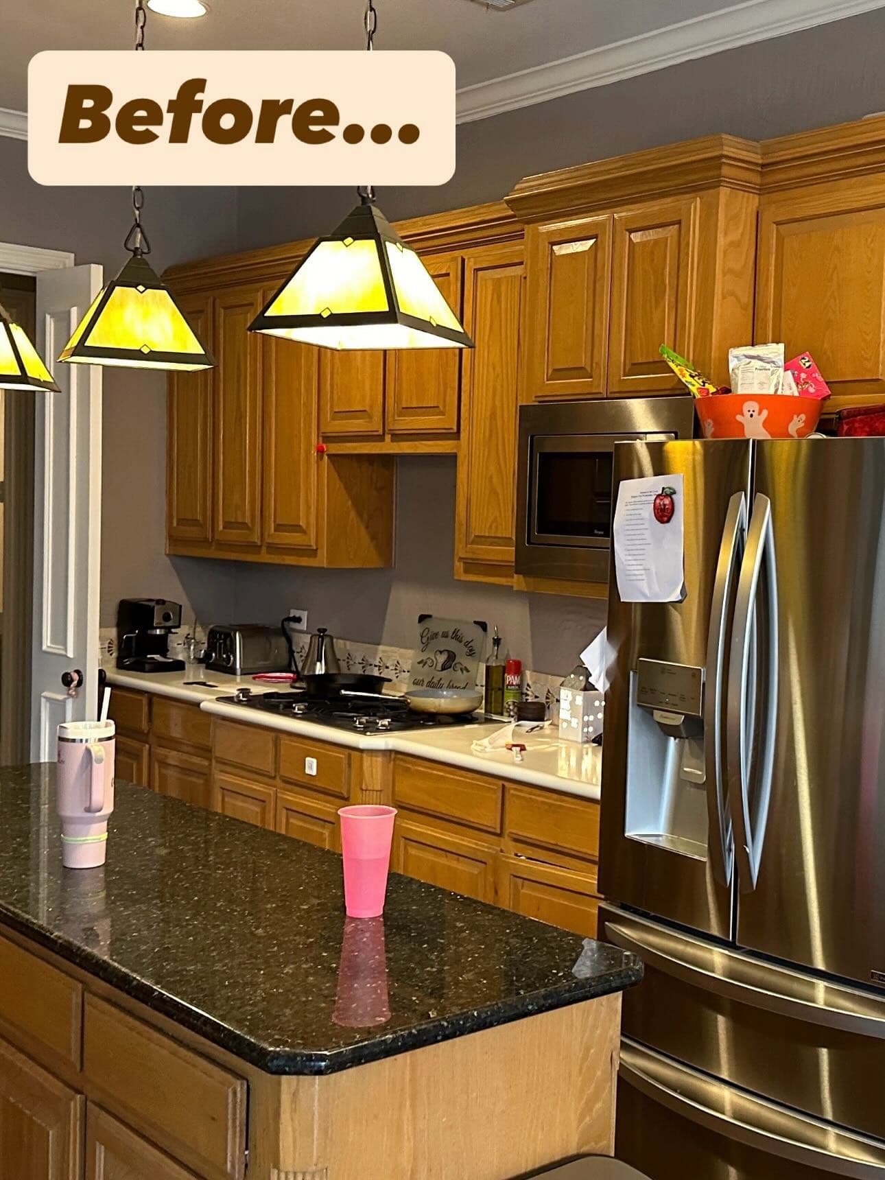 The same kitchen before the work, with dark timber cabinets, a dark stone worktop and stained-glass pendant lights
